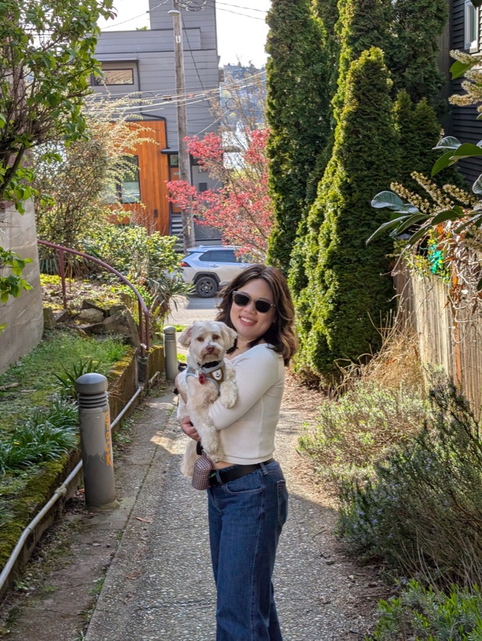 Sojin Oh smiling outdoors, holding her dog